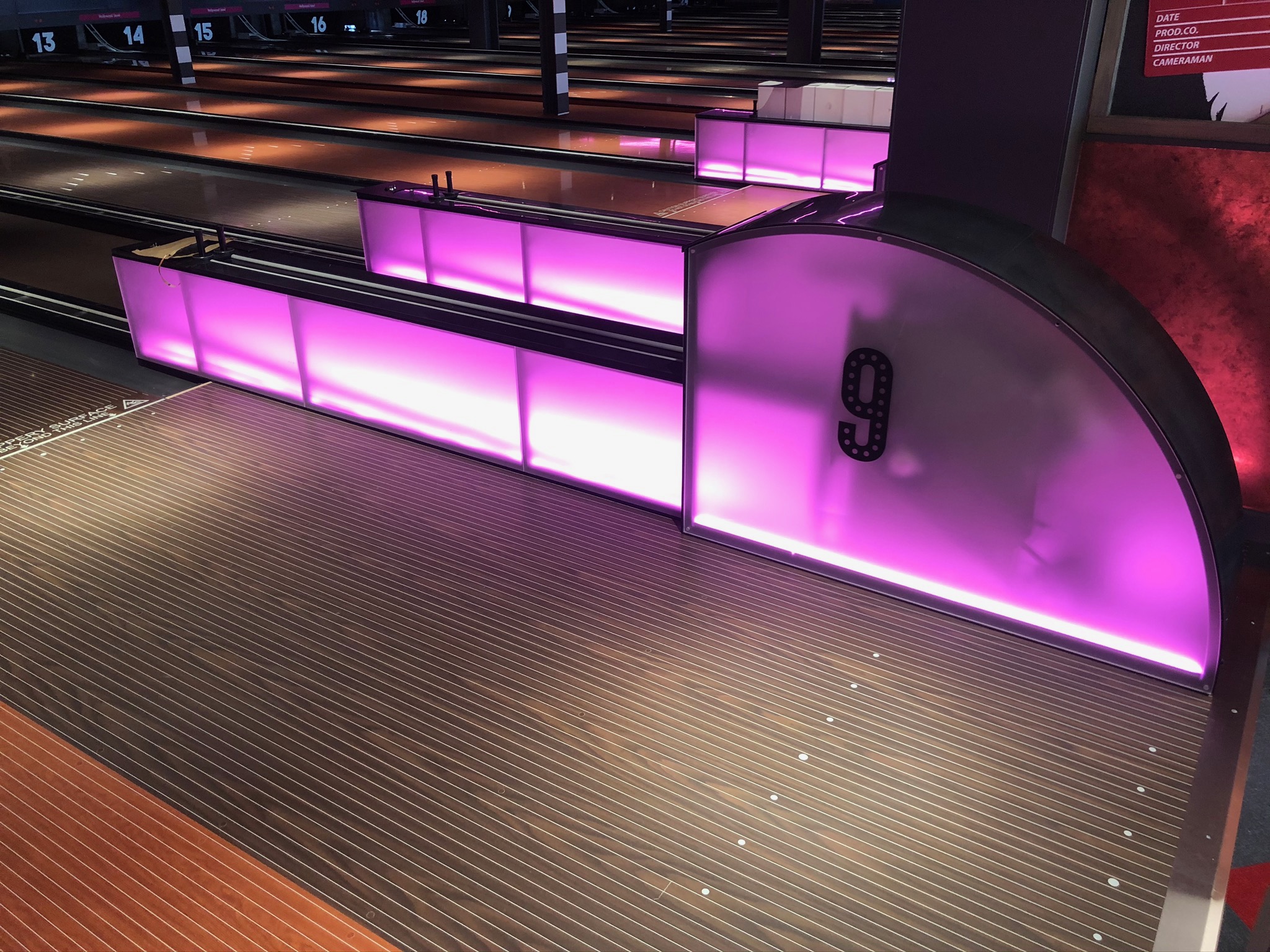 Hollywood Bowl York bespoke illuminated ball return housing with purple LED panels and lane-side seating — manufactured and installed by Novus